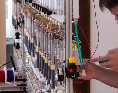 A series of pipes on an aluminum frame with someone attaching a controller to one of them.