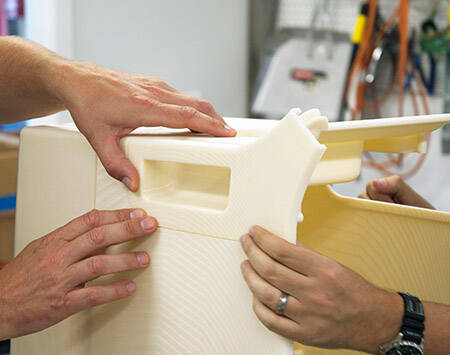 Three hands assembling the SLA prints of an intra-aortic balloon puump cart
